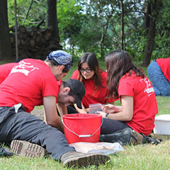 Colour photograph of five trainee archaeologists working in an excavation pit. They are all wearing red shirts.