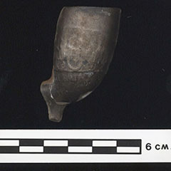 Colour photograph of a bowl pipe made of clay. The piece is blackened.