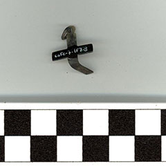 Colour photograph of a small twisted cross made of copper alloy. The Borden Code is visible.