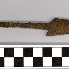 Colour photograph of a rusted iron harpoon head.