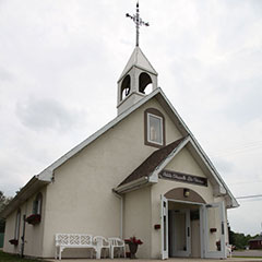 Photographie couleur d'une chapelle blanche et de son clocher.