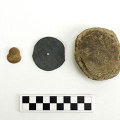 Colour photograph of a small anthropomorphic figure, an engraved slate disc and an engraved stone.