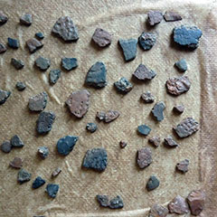 Colour photograph of a set of pottery shards. Colours vary from orange-red to black. All pieces have different shapes and sizes.