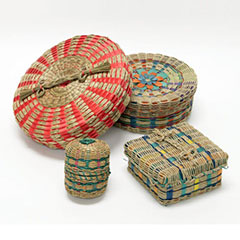 Colour photograph of four black ash baskets. They all have different shapes and sizes and are decorated in bright colors.