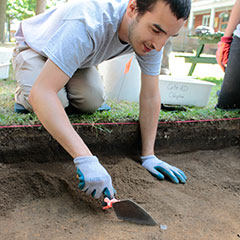 Photographie couleur d'un apprenti-archéologue lors de la découverte d'une partie d'un fourneau de pipe.