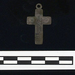 Photographie couleur d'un pendentif en croix fait d'alliage cuivreux.