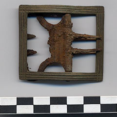 Colour photograph of a rusted shoe buckle.