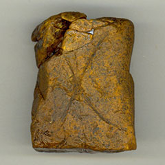 Colour photograph of a piece of rectangular shaped yellow argillite onto which a cross is engraved.