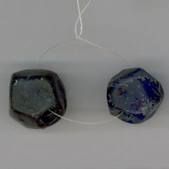 Colour photograph of two faceted glass blue beads on a thread.
