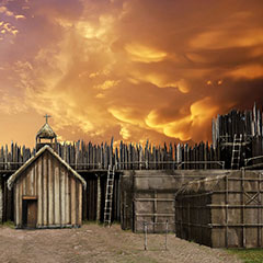 Illustration couleur de quelques maisons longues et d'une église en bois. Le village est protégé par une palissade. Le ciel est enflammé.