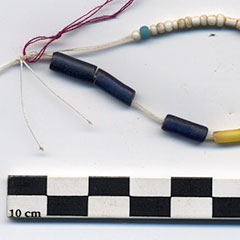 Photographie couleur de perles de traite en verre blanc et perles tubulaires bleues et blanches.